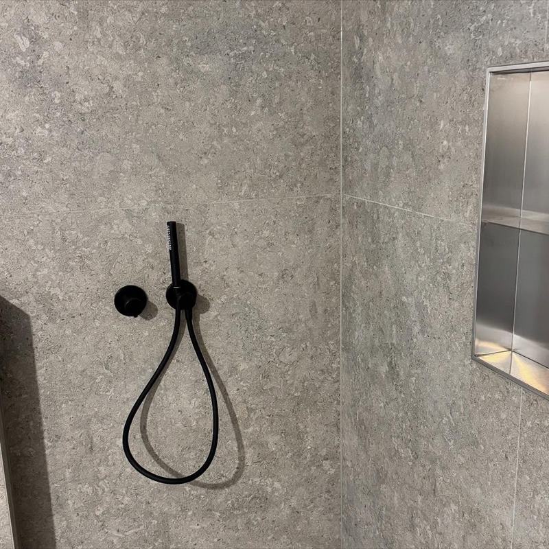 Dusche mit schwarzer Handbrause und Wandnische