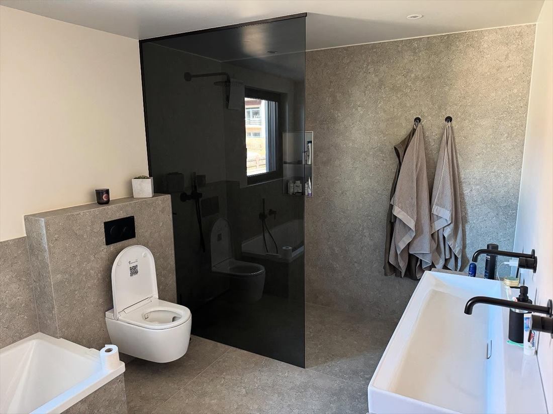 Bad mit dunkler Wandgestaltung, wandhängendem WC und Badewanne
