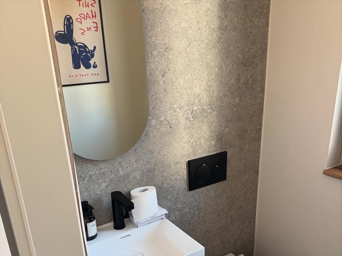 Gäste-WC mit rundem Spiegel und Wand in Steinoptik