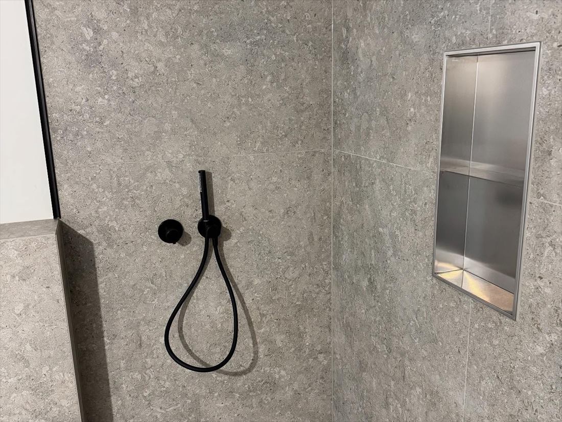 Dusche mit schwarzer Handbrause und Wandnische